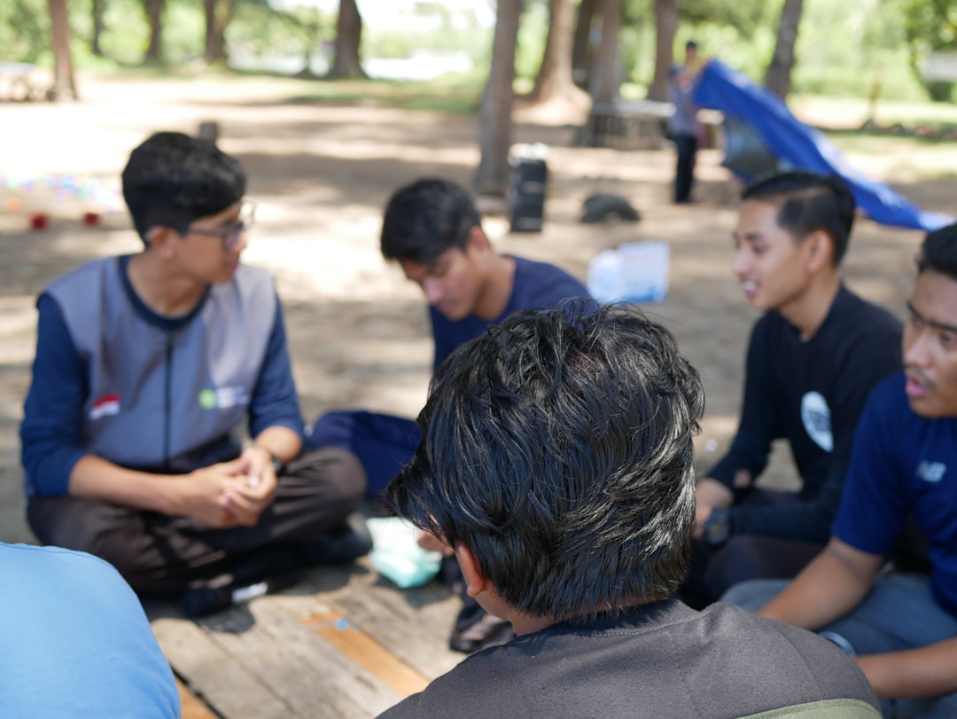 a-group-of-young-men-sitting-on-top-of-a-wooden-bench-u-gfmqgvizo