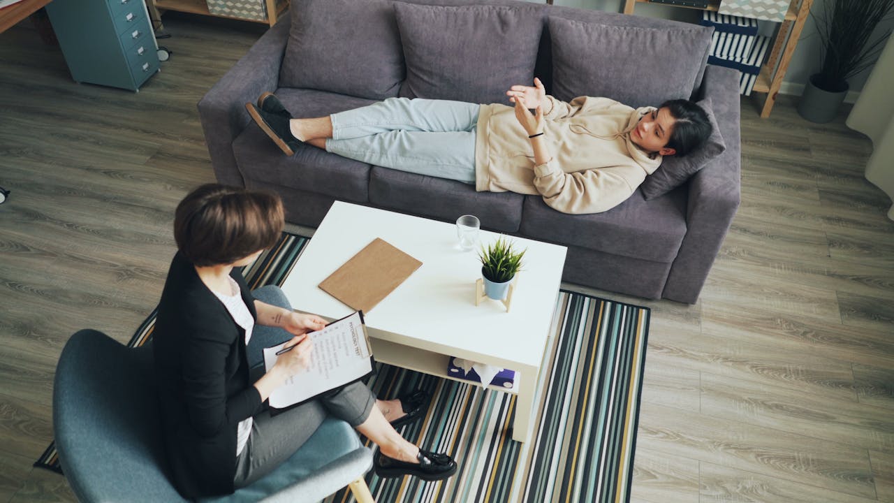 A psychotherapy session with a therapist consulting a client indoors on a sofa.