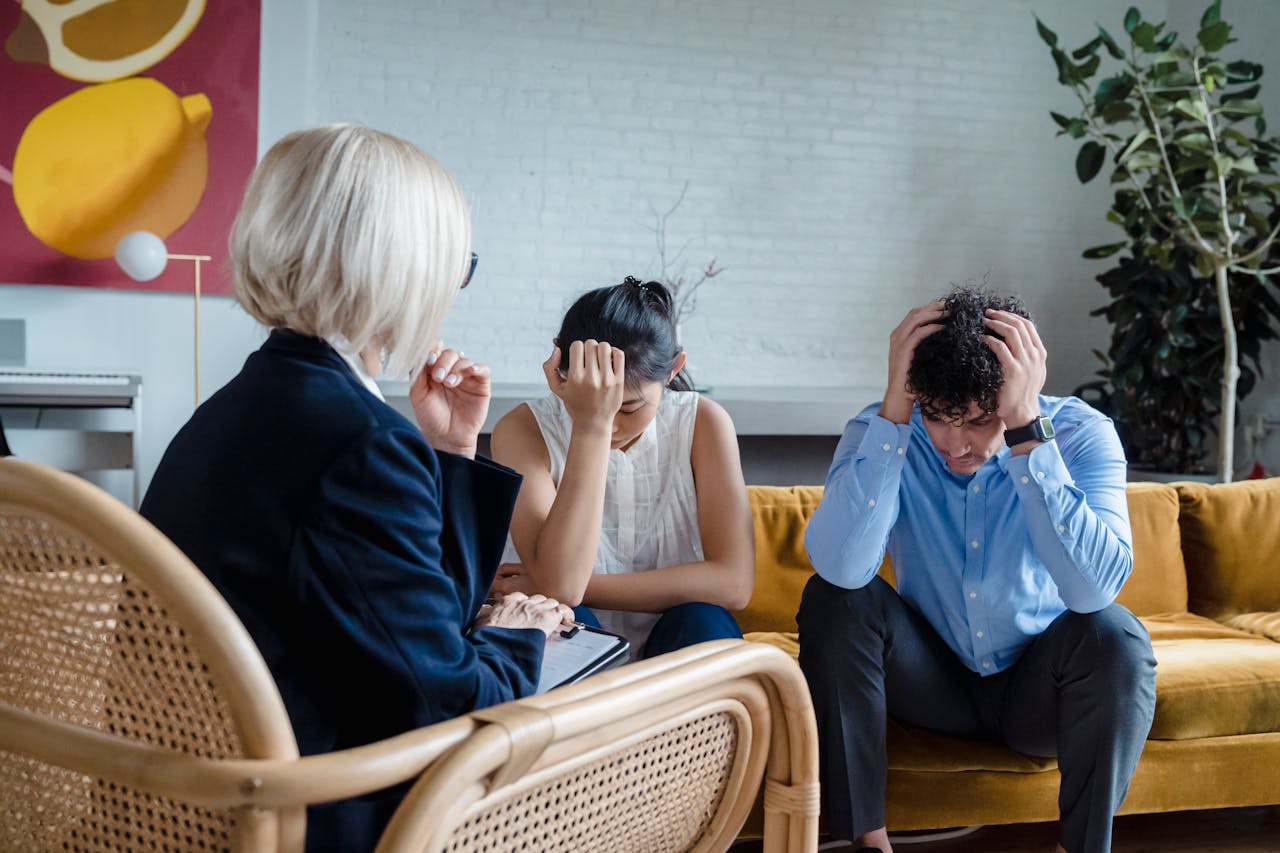 Stressed couple in therapy with a psychologist, discussing relationship issues.